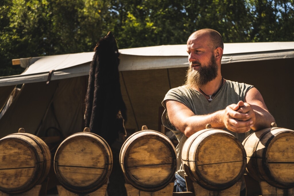 man with beard leaning on beer barrels