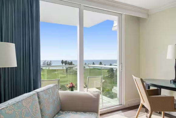 view of ocean from double room with sofa and desk