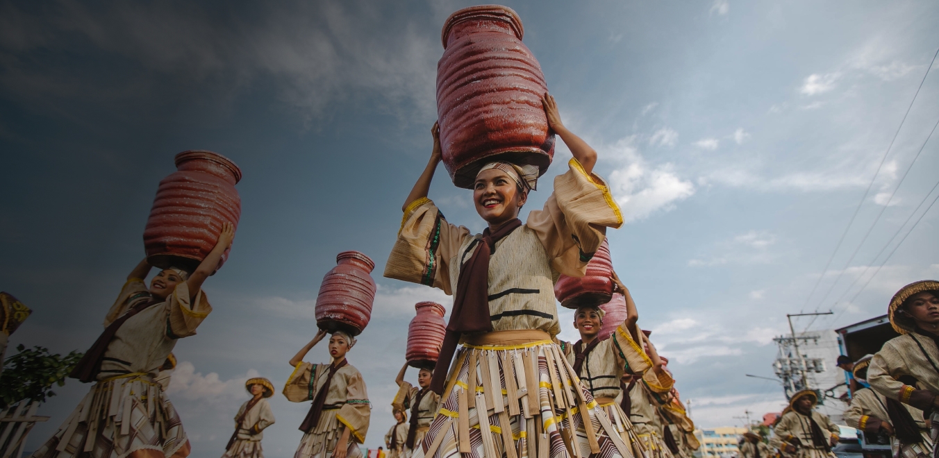 Women carrying clay pots on heads smiling wearing traditional robes